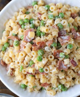 ditalini pasta with peas and bacon in white bowl