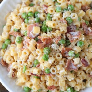 ditalini pasta with peas and bacon in white bowl