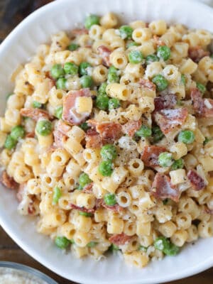 ditalini pasta with peas and bacon in white bowl
