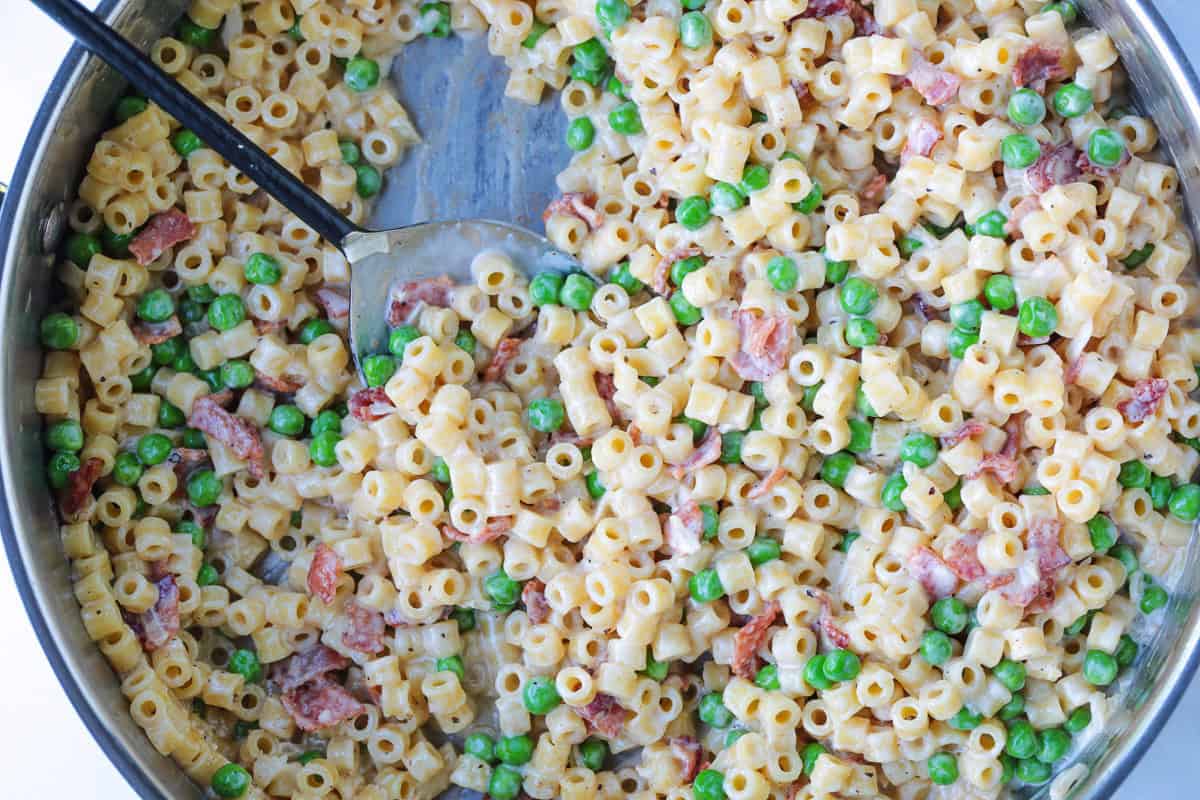 This creamy Bacon and Pea Ditalini pasta can be served as a side dish to dinner or as a meal on its own. Ready in 30 and sure to please! bacon and pea ditalini in skillet with spoon