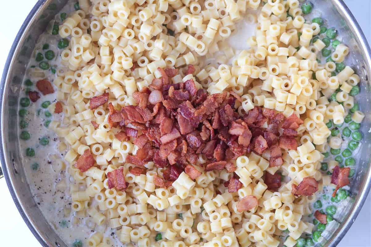 This creamy Bacon and Pea Ditalini pasta can be served as a side dish to dinner or as a meal on its own. Ready in 30 and sure to please! ditalini pasta in a skillet with bacon and peas in a cream sauce