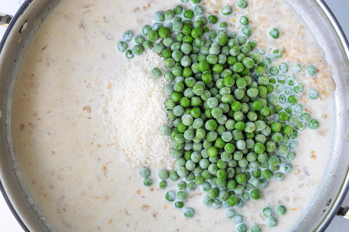 This creamy Bacon and Pea Ditalini pasta can be served as a side dish to dinner or as a meal on its own. Ready in 30 and sure to please! cream, parmesan cheese and peas in a skillet