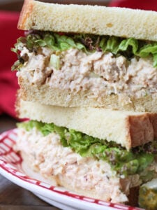 chicken salad sandwich stacked on a plate with pickle