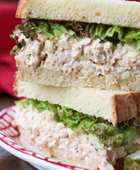 chicken salad sandwich stacked on a plate with pickle