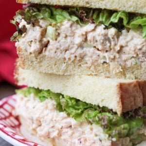 chicken salad sandwich stacked on a plate with pickle