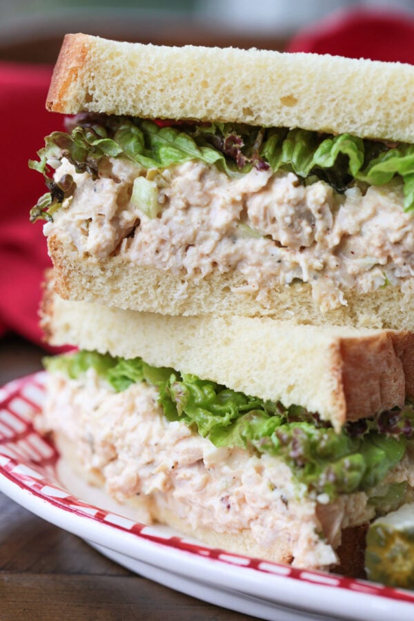 chicken salad sandwich stacked on a plate with pickle