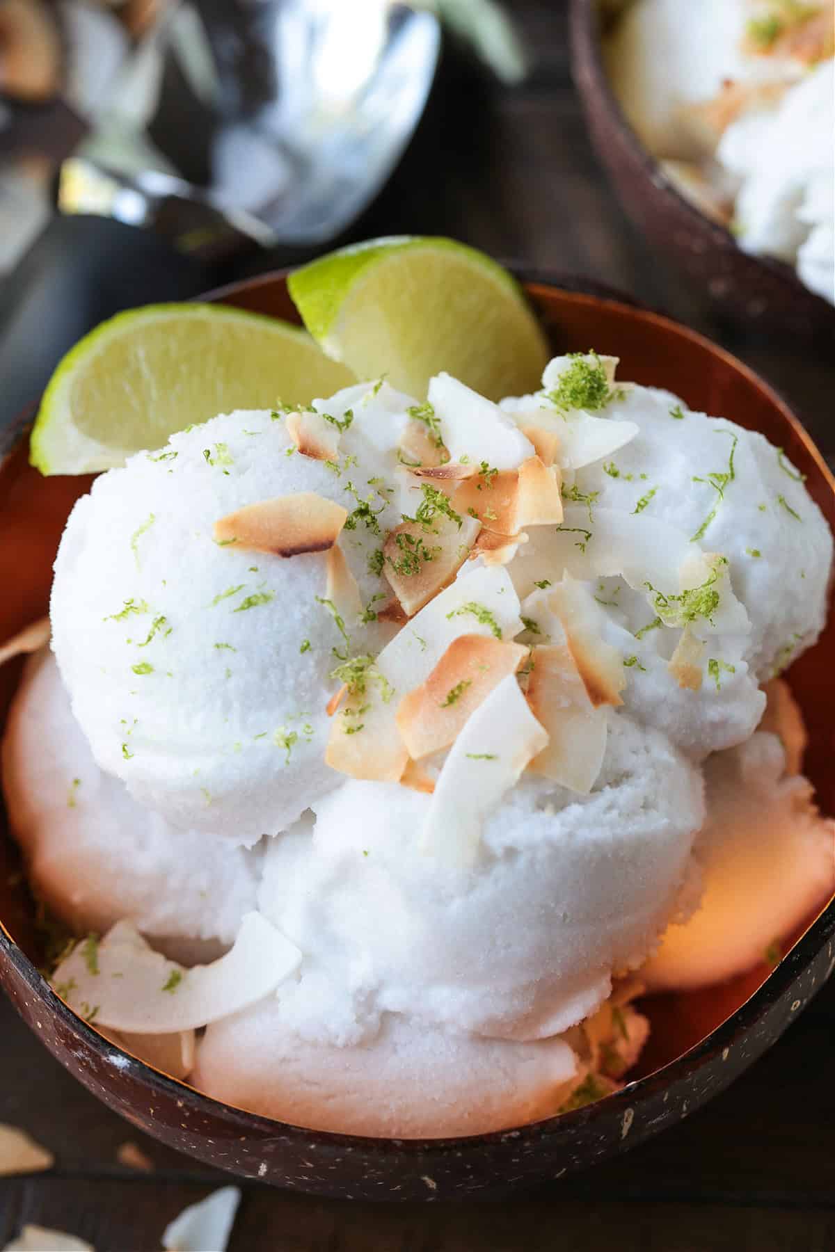 This homemade coconut sorbet is bursting with tropical flavor! Made with coconut milk and simple ingredients for a refreshing summer dessert. coconut sorbet in bowl with limes