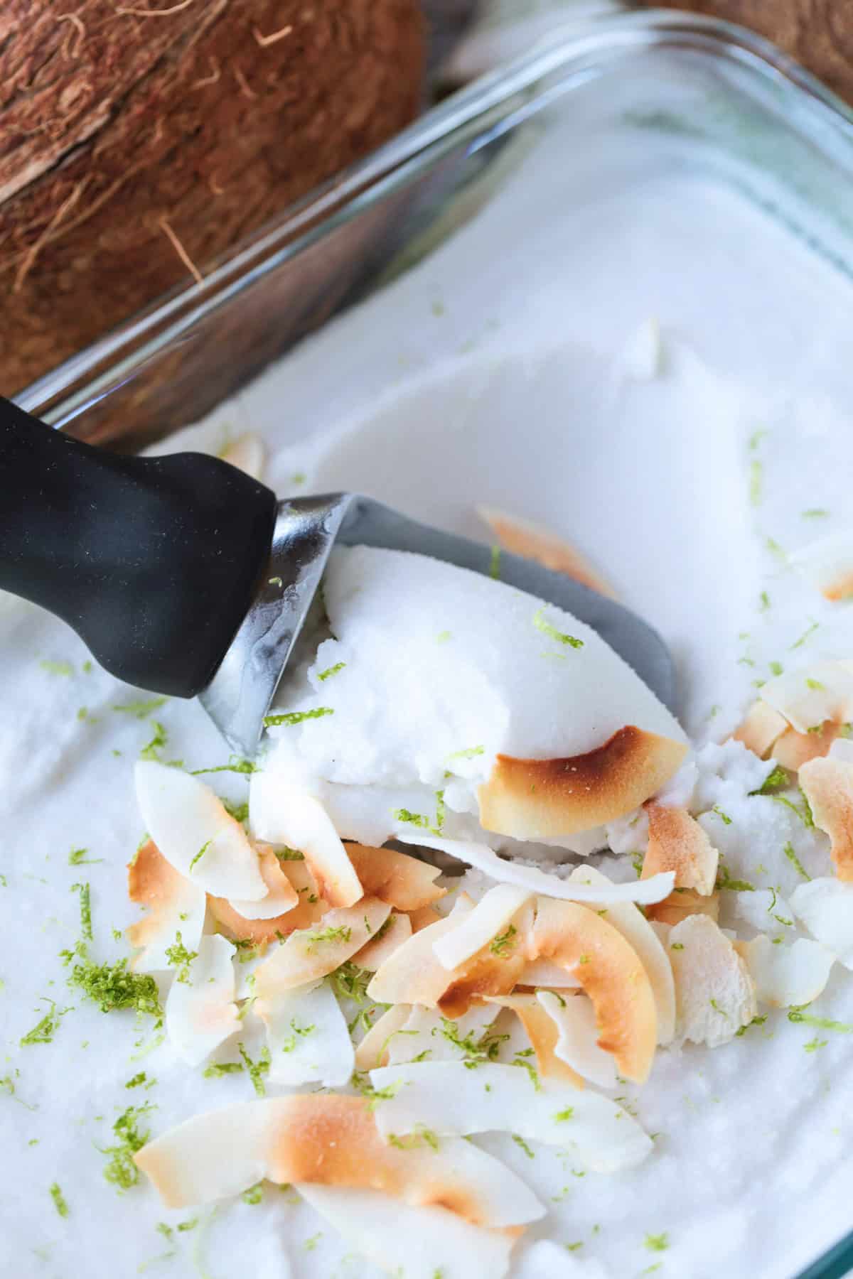 This homemade coconut sorbet is bursting with tropical flavor! Made with coconut milk and simple ingredients for a refreshing summer dessert. scooping sorbet out of dish