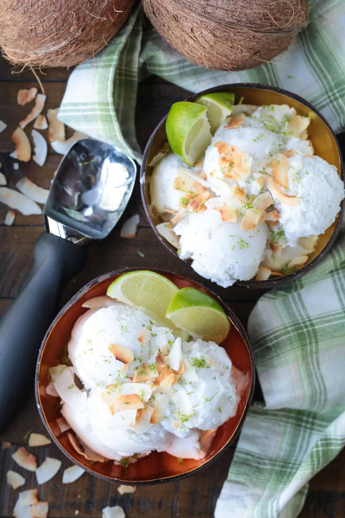 This homemade coconut sorbet is bursting with tropical flavor! Made with coconut milk and simple ingredients for a refreshing summer dessert. two bowls of coconut sorbet with scooper in background