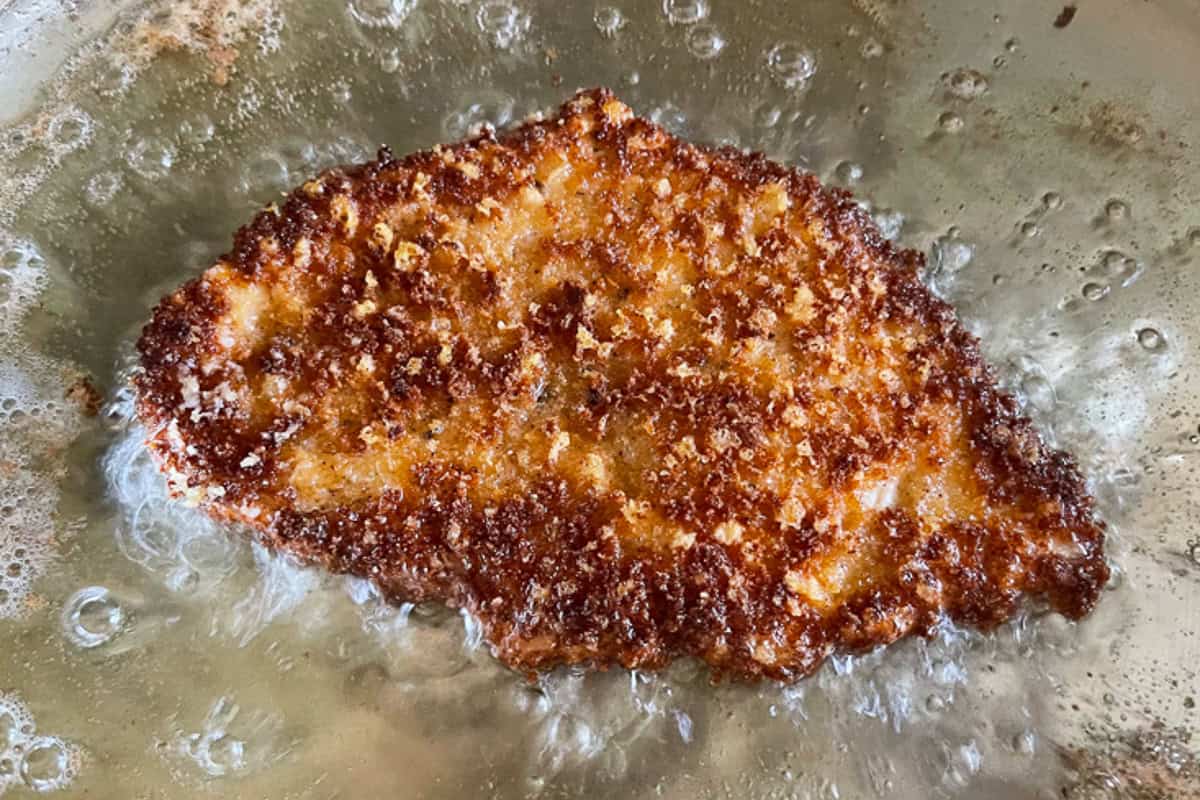 Super crispy chicken parmesan, not made soggy form baking in sauce. Serve over pasta or on a plate with marinara for the ultimate crispiness! crispy chicken cutlet frying in oil