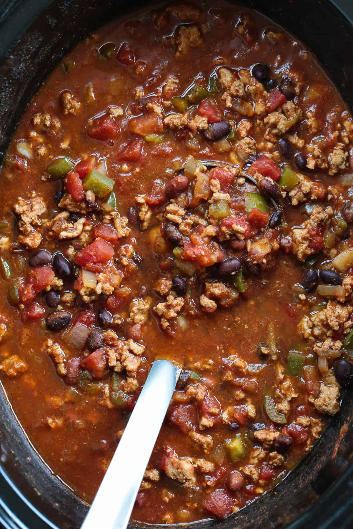 This slow cooker turkey chili is packed with lean ground turkey, vegetables and vibrant spices. Perfect for easy dinners or game days! turkey chili in a slow cooker with ladle