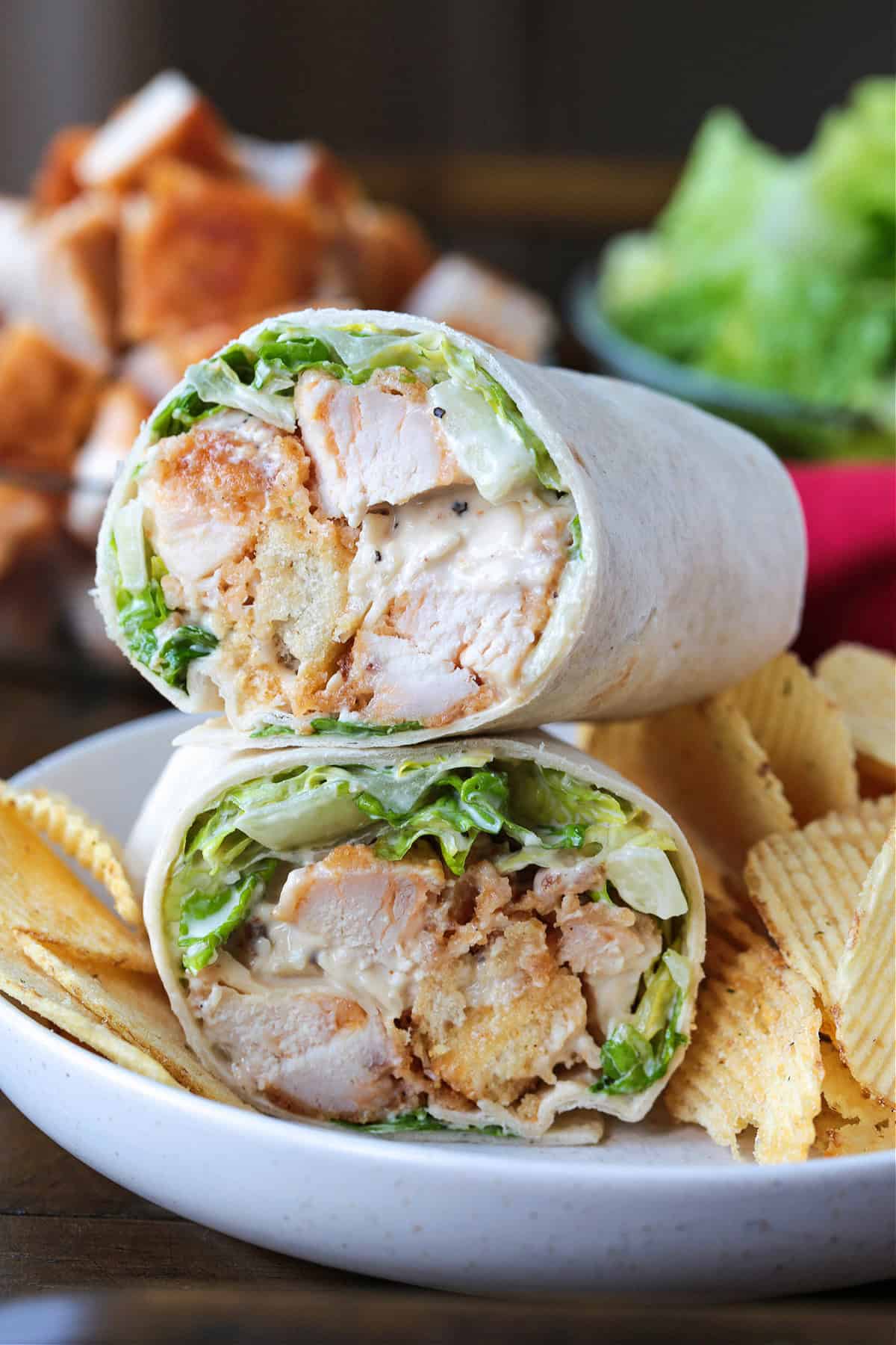 This Chicken Caesar Wrap made with our homemade Caesar dressing is the ultimate quick meal. A tasty lunch or dinner that's ready in minutes! chicken caesar wrap cut and stacked on a plate with potato chips