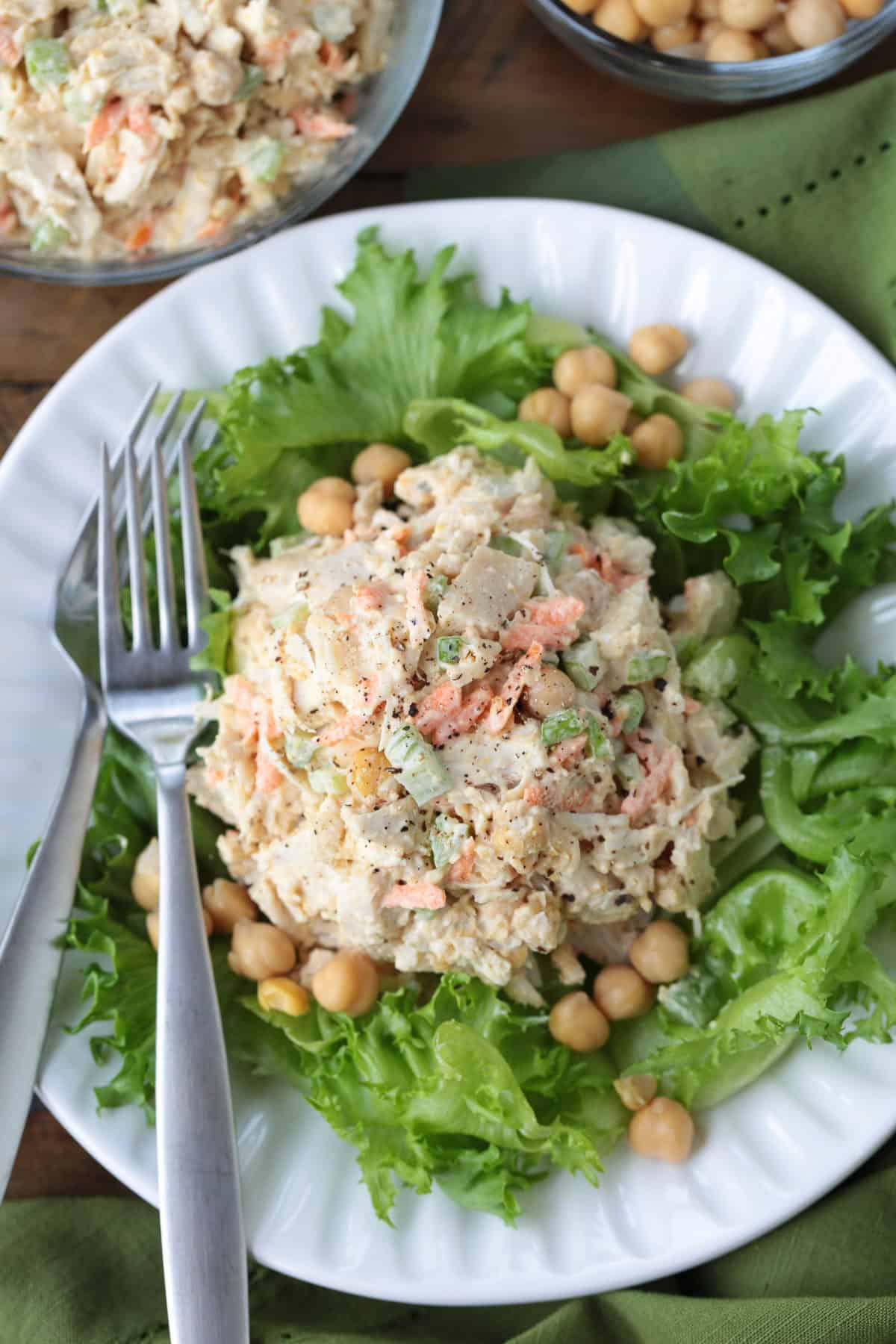 Chickpea Chicken Salad is made with tender chicken, crunchy veggies and buttery chickpeas. A protein packed meal that's ready in minutes! chickpea chicken salad on a bed of lettuce with forks