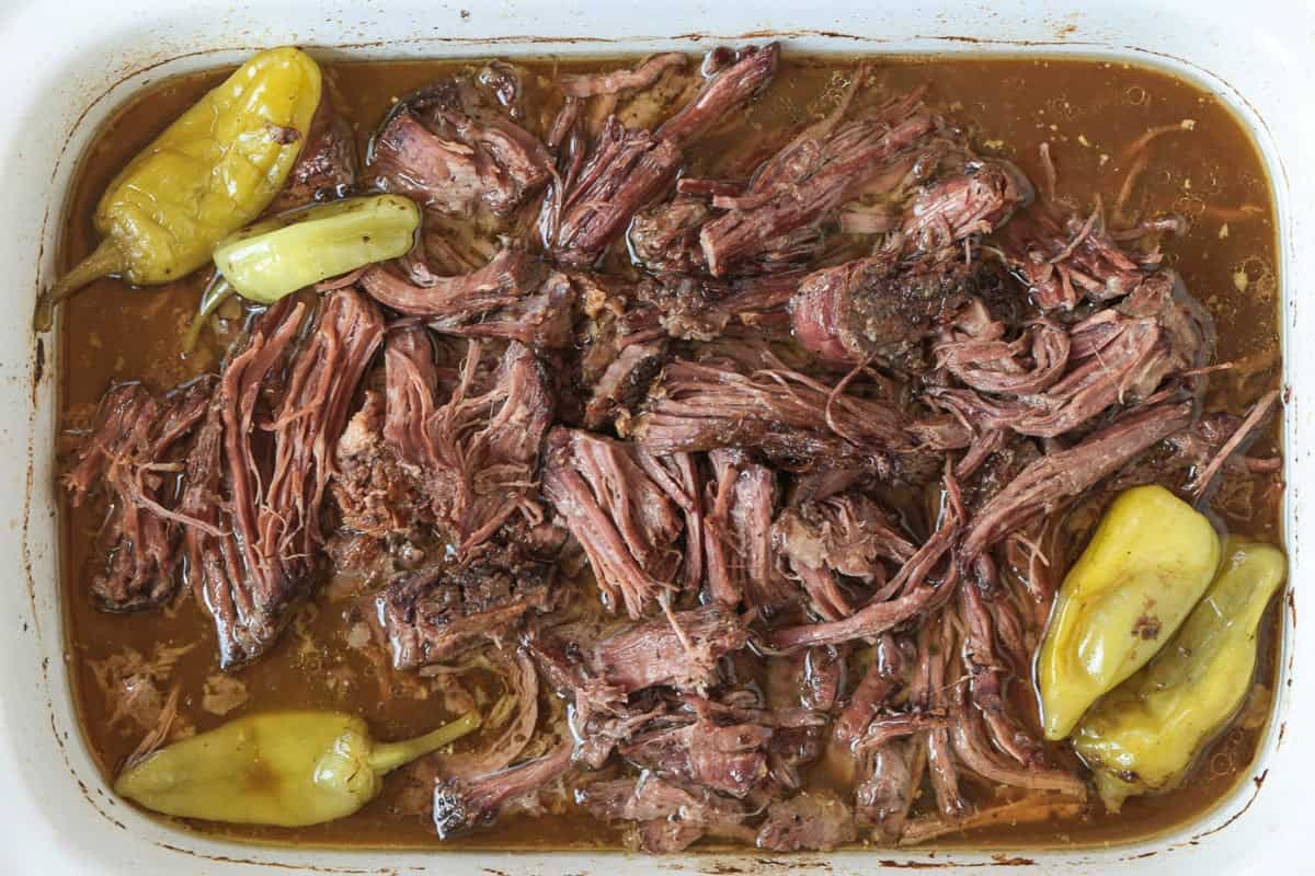 Slow Cooker Mississippi Pot Roast is tender and delicious in a tangy brown gravy. An easy crock pot dinner the whole family will love! shredded pot roast in slow cooker with peppers