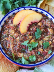 peach mango salsa in a bowl with peach slices on the side