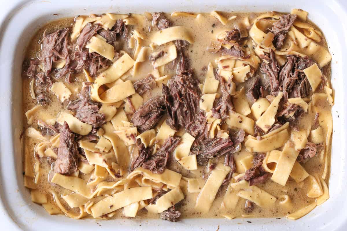 shredded beef in slow cooker with noodles and gravy
