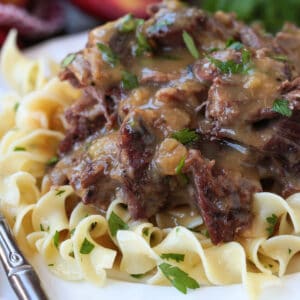pot roast with gravy on a plate with noodles