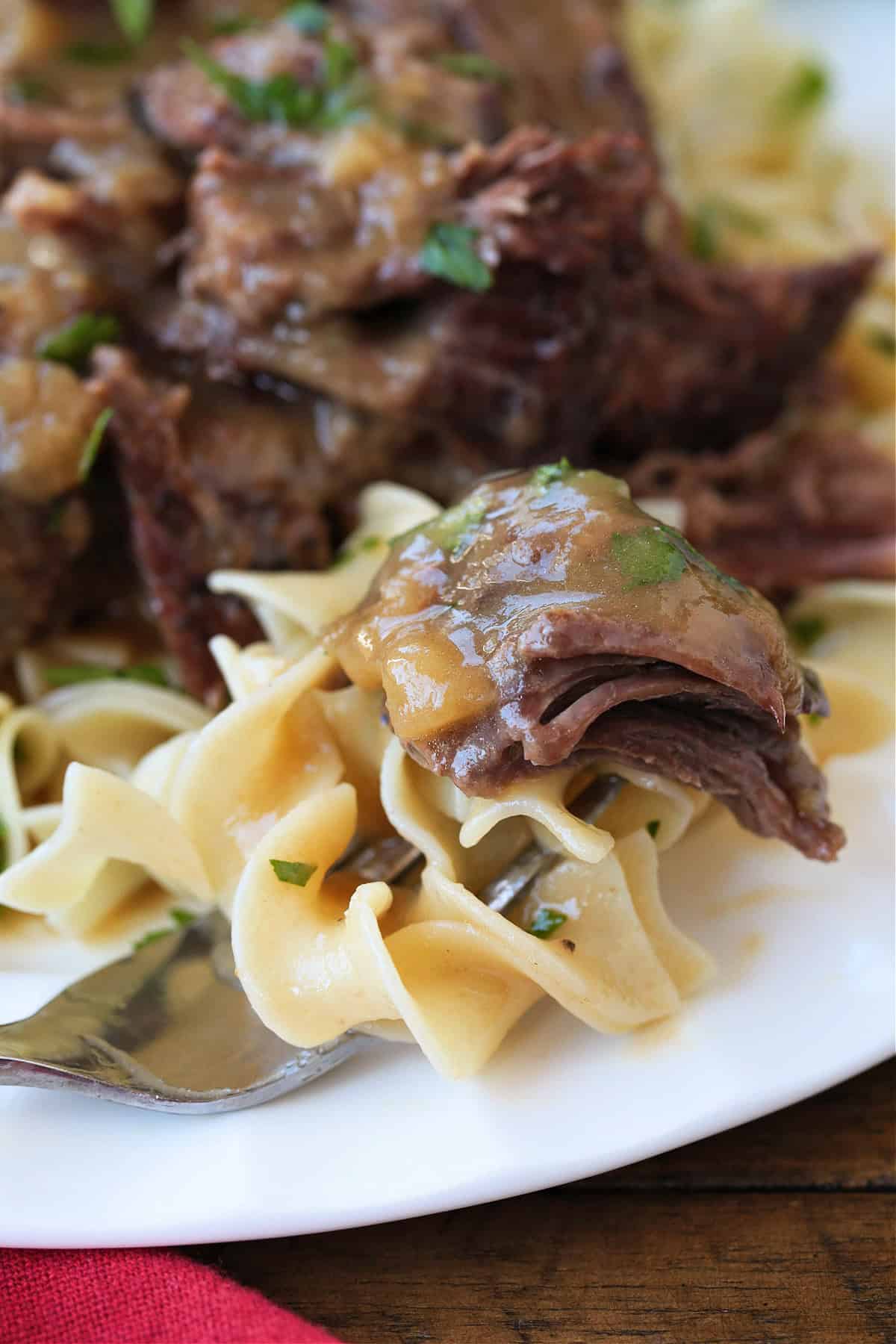 pot roast with gravy on fork with noodles