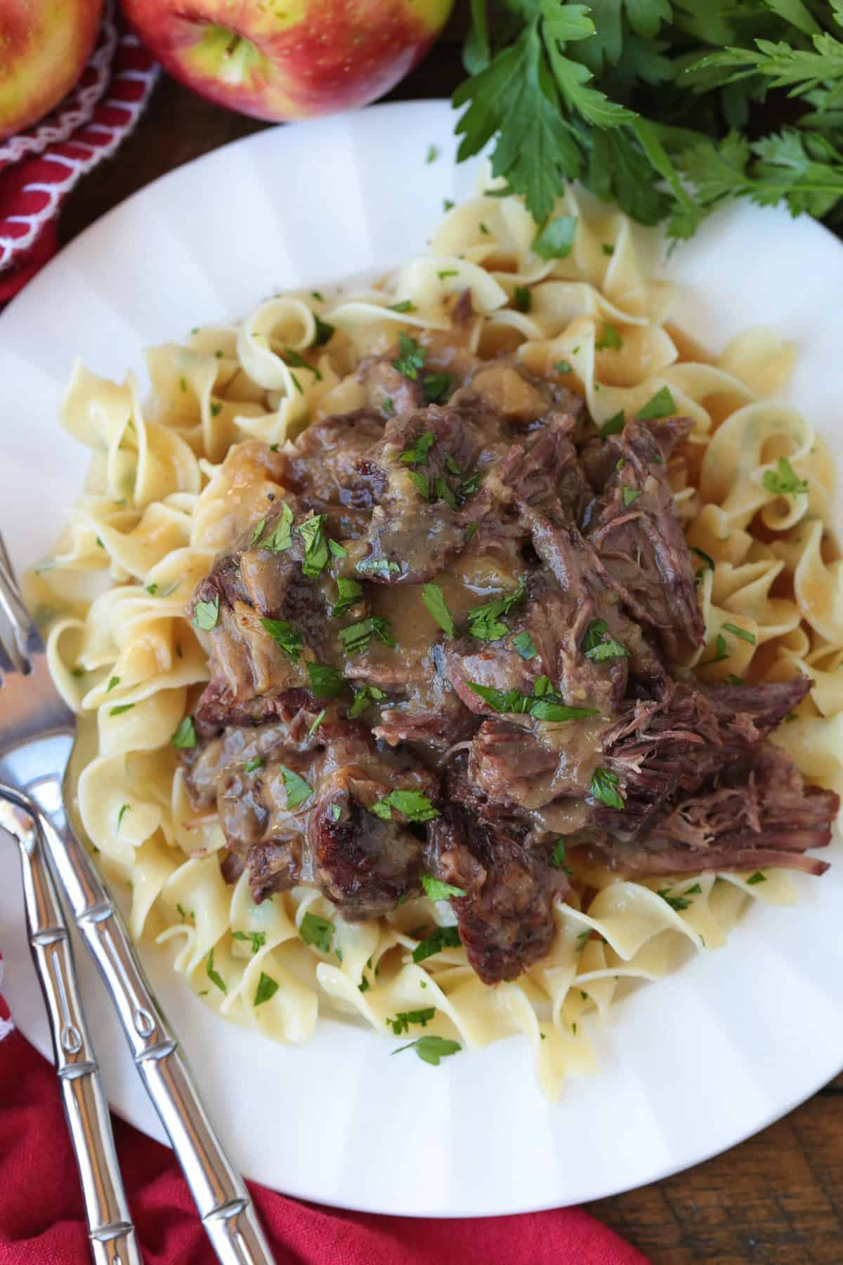 pot roast with apple cider over noodles on plate