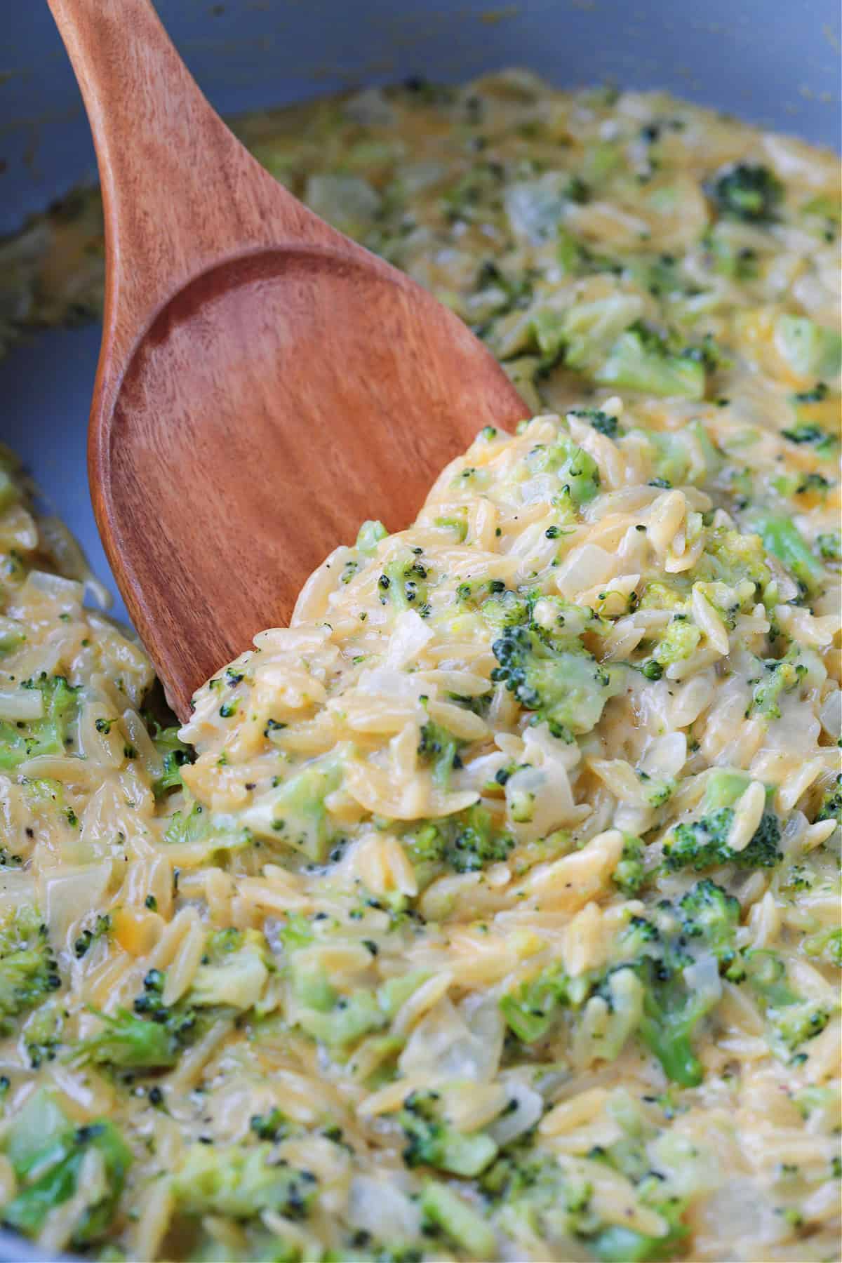 This Cheesy Broccoli Orzo is the ultimate comfort food side dish! Perfect alongside chicken or steak, or on its own for an easy, cozy dinner. up close scoop of broccoli cheddar orzo