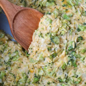 broccoli and cheese orzo in a pot with a wooden serving spoon
