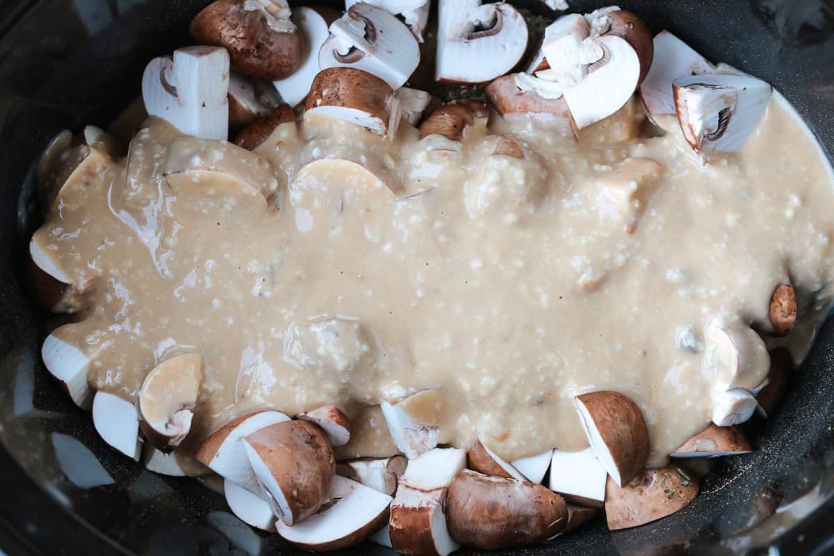 This cozy Slow Cooker Chicken Stroganoff is creamy and hearty, we love it for busy weeknights or lazy weekends. An easy comfort food dinner! gravy poured over mushrooms and chicken in a crock pot