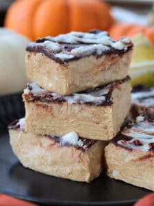 pumpkin fudge cut into squares and stacked on a black plate