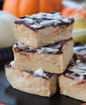 pumpkin fudge cut into squares and stacked on a black plate