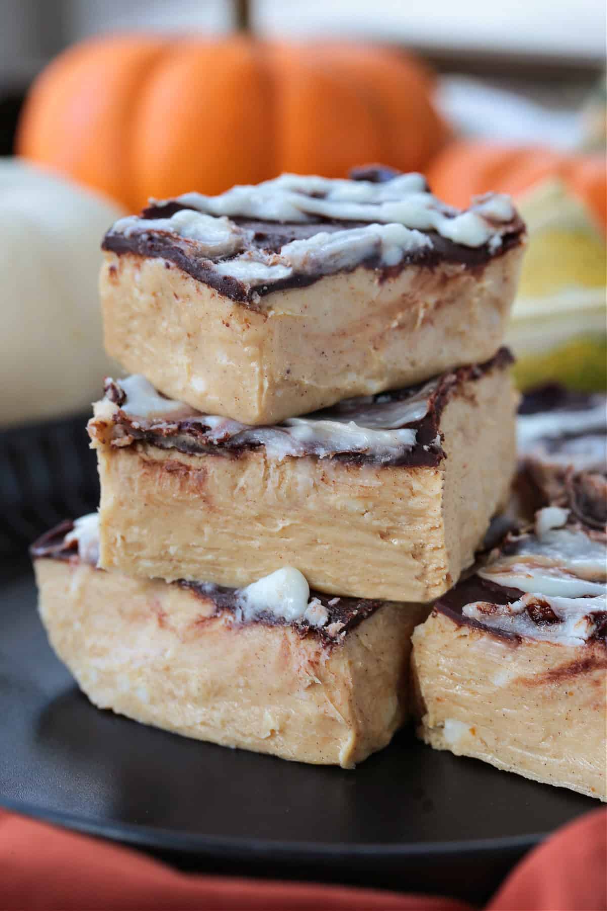 pumpkin fudge cut into squares and stacked on a black plate
