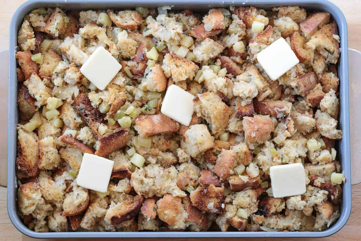 uncooked stuffing in a baking dish with butter on top