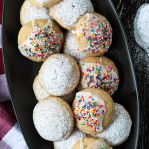 italian wedding cookies on black platter with checkered napkin