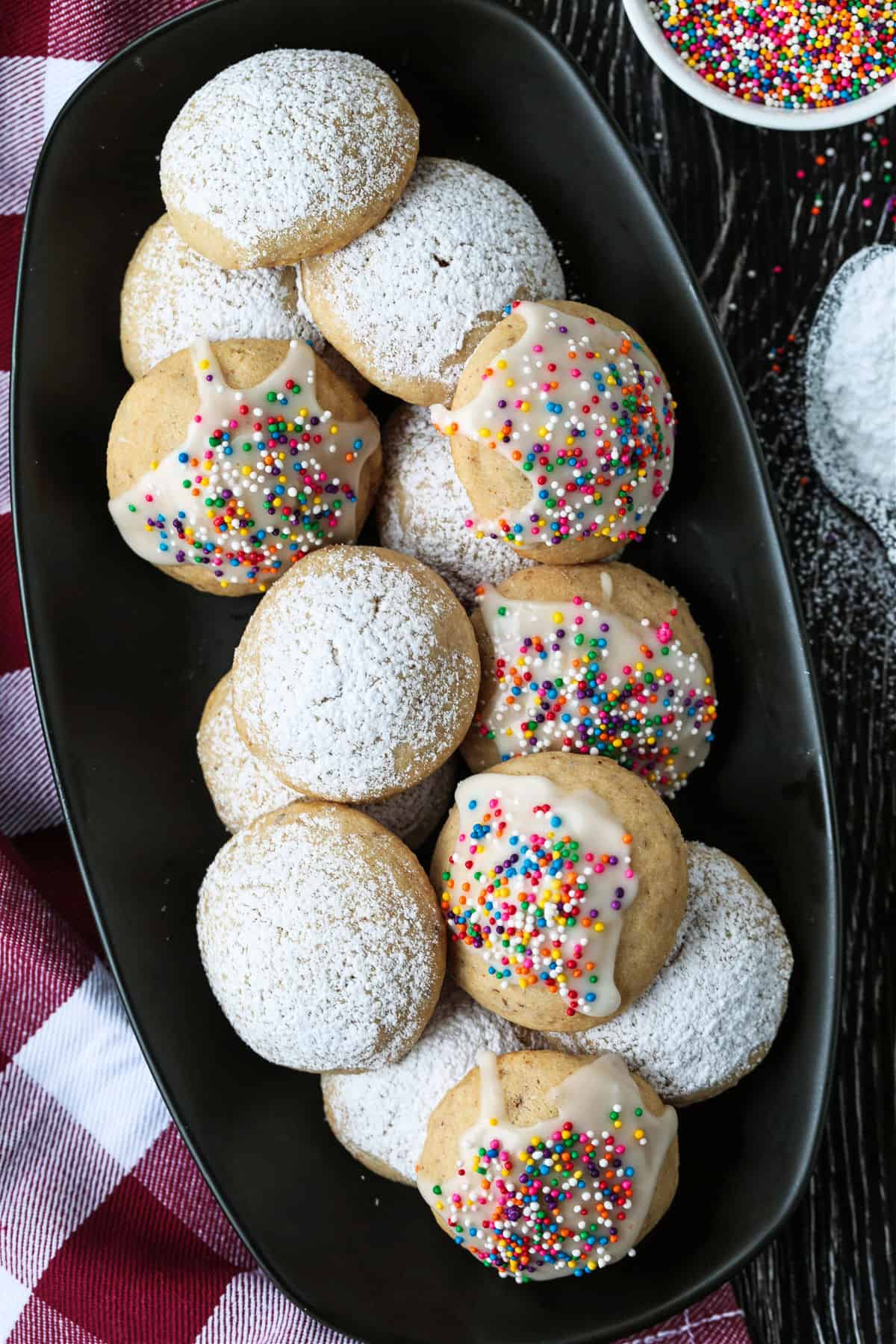 italian wedding cookies on black platter with checkered napkin