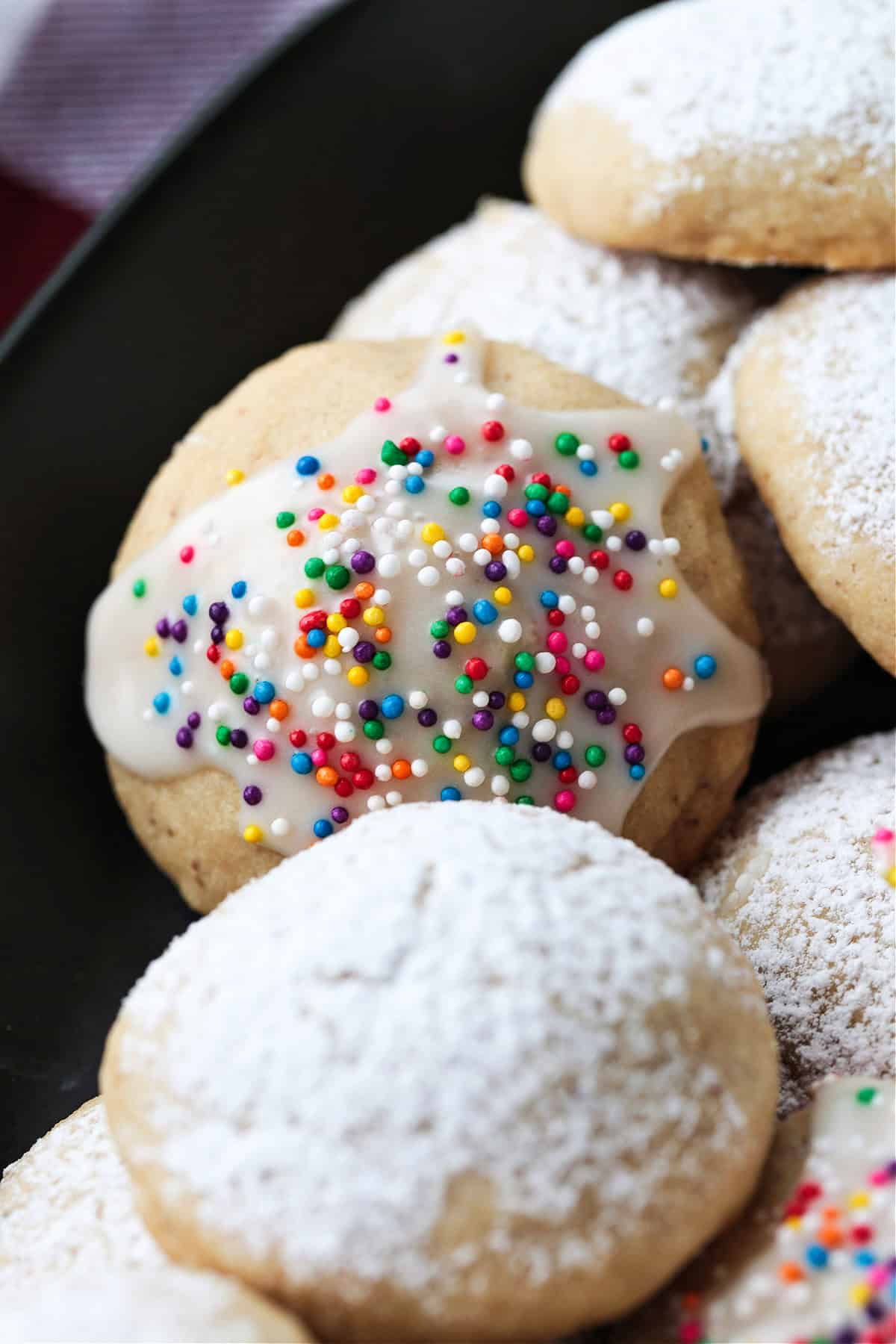 italian wedding cookies with powdered sugar and sprinkles on black platter