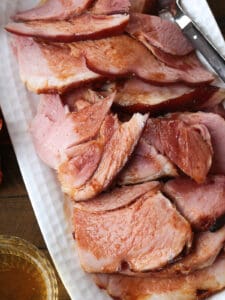 sliced ham on a platter with a glass of beer on the side