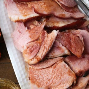 sliced ham on a platter with a glass of beer on the side