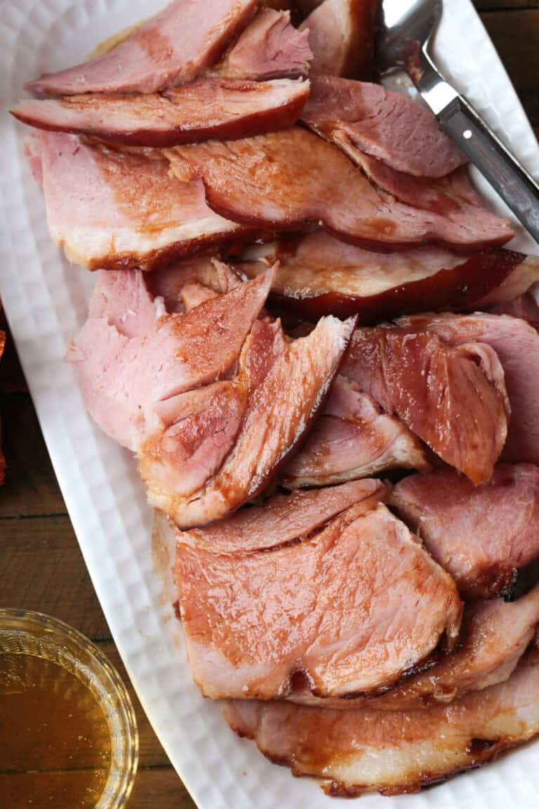 sliced ham on a platter with a glass of beer on the side