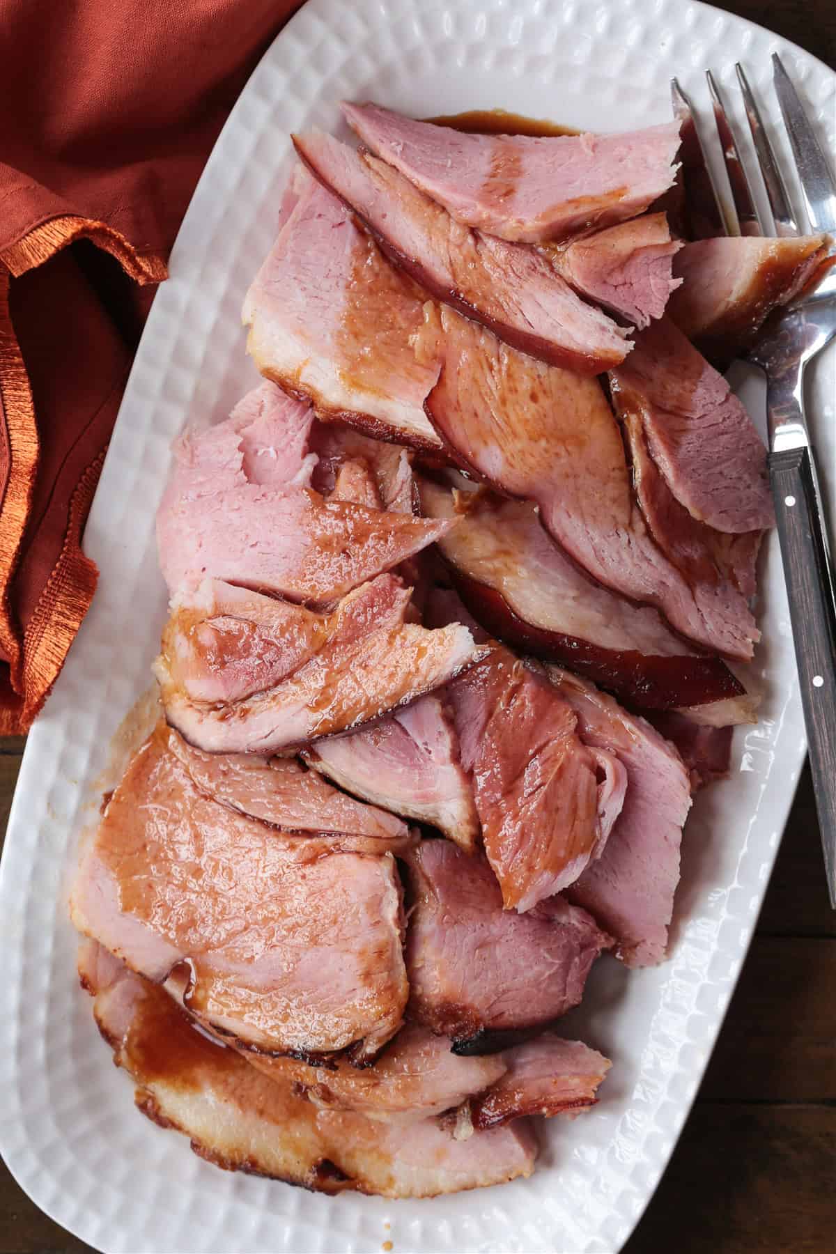 sliced ham on white platter with beer glaze