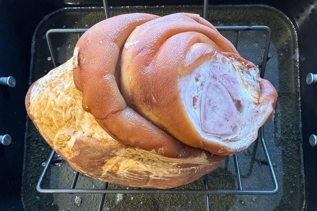 unbaked ham on a rack over a pan with beer