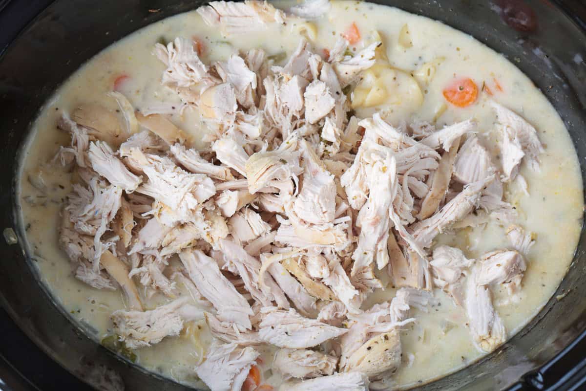 shredded chicken in a slow cooker with a creamy broth