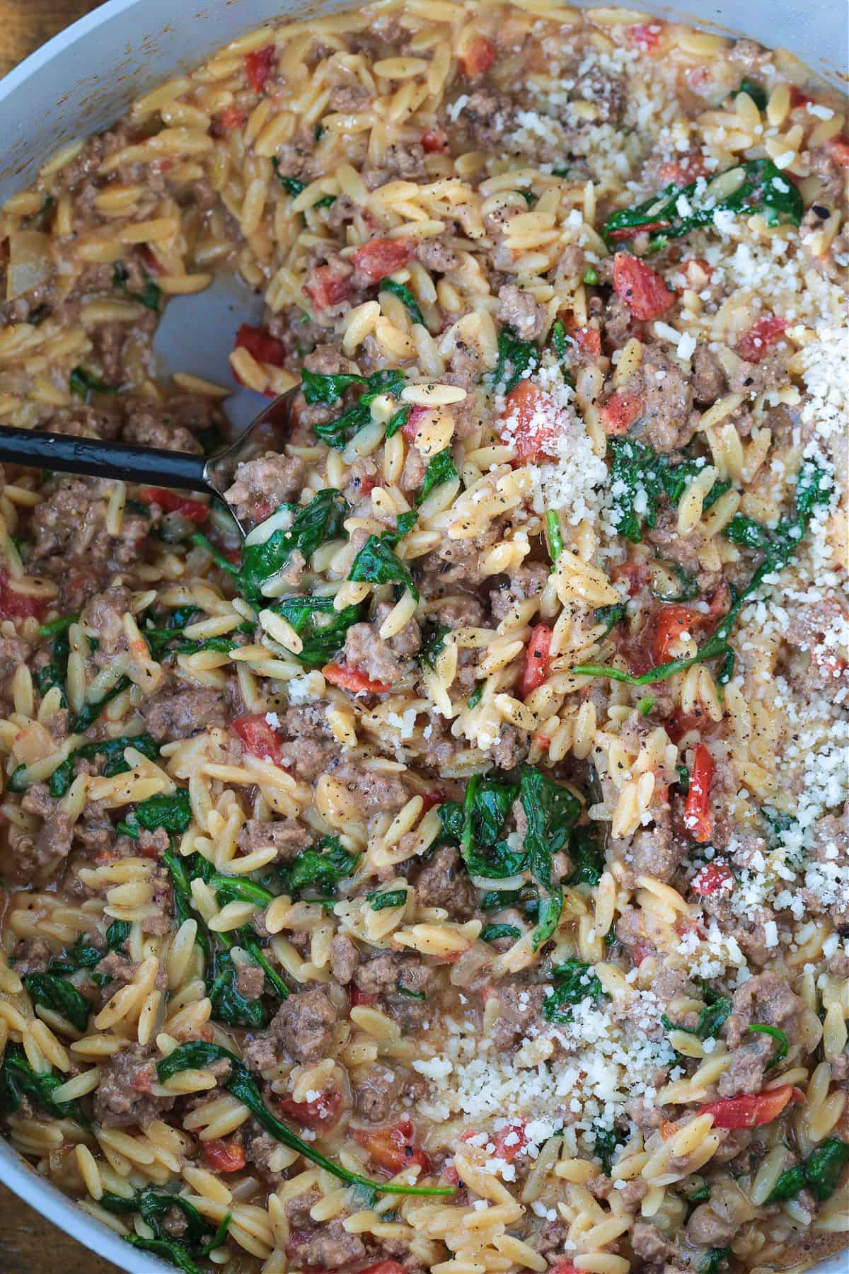 Spinach and Beef Orzo is a comfort food meal that's done in 30 minutes! Tender orzo with ground beef and spinach in a cheesy, creamy sauce. ground beef and spinach orzo in pot with spoon