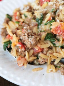 a spoonful of ground beef and spinach orzo on a white plate