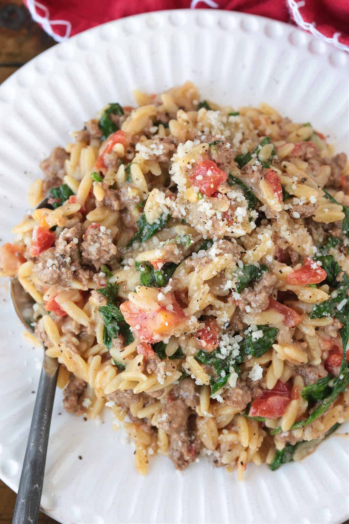 spinach and beef orzo on a white plate with spoon