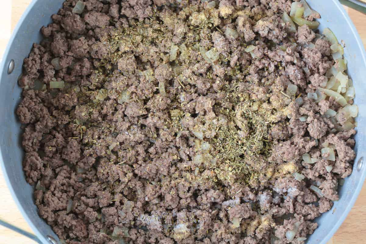 Spinach and Beef Orzo is a comfort food meal that's done in 30 minutes! Tender orzo with ground beef and spinach in a cheesy, creamy sauce. ground beef in a skillet with seasonings