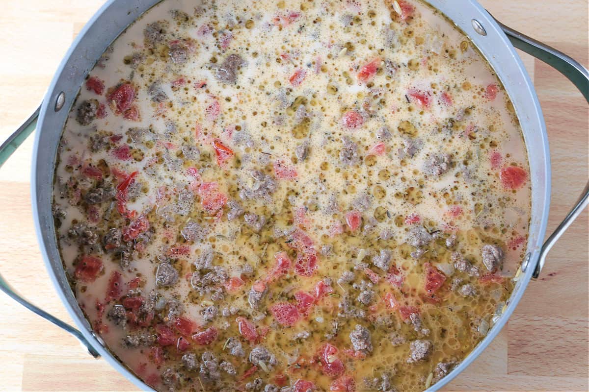 Spinach and Beef Orzo is a comfort food meal that's done in 30 minutes! Tender orzo with ground beef and spinach in a cheesy, creamy sauce. broth in a skillet with ground beef, vegetables and orzo