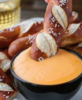 pretzel stick dipping into beer cheese dip