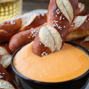 pretzel stick dipping into beer cheese dip