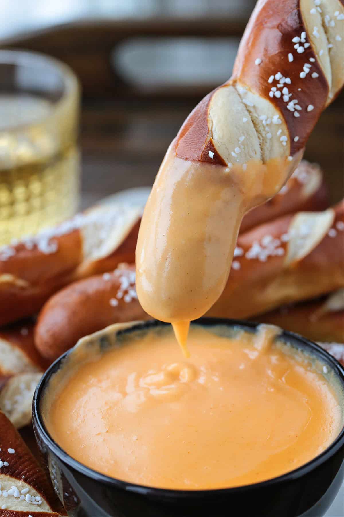 pretzel stick dipped in beer cheese with a drip