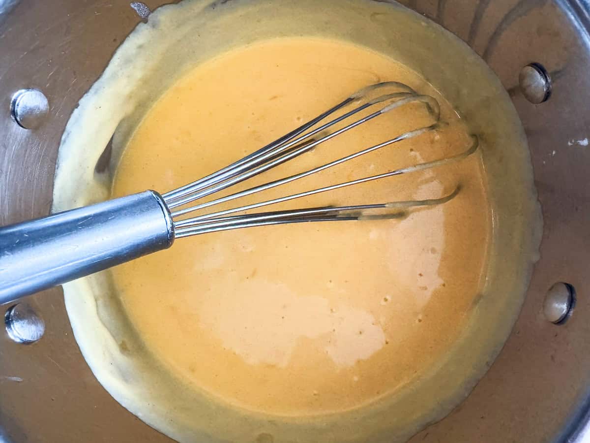 cheese sauce in a pot with a whisk