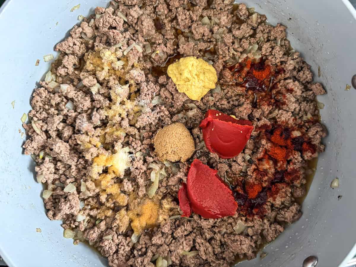 ground beef in a skillet with mustard, tomato paste, brown sugar and seasonings