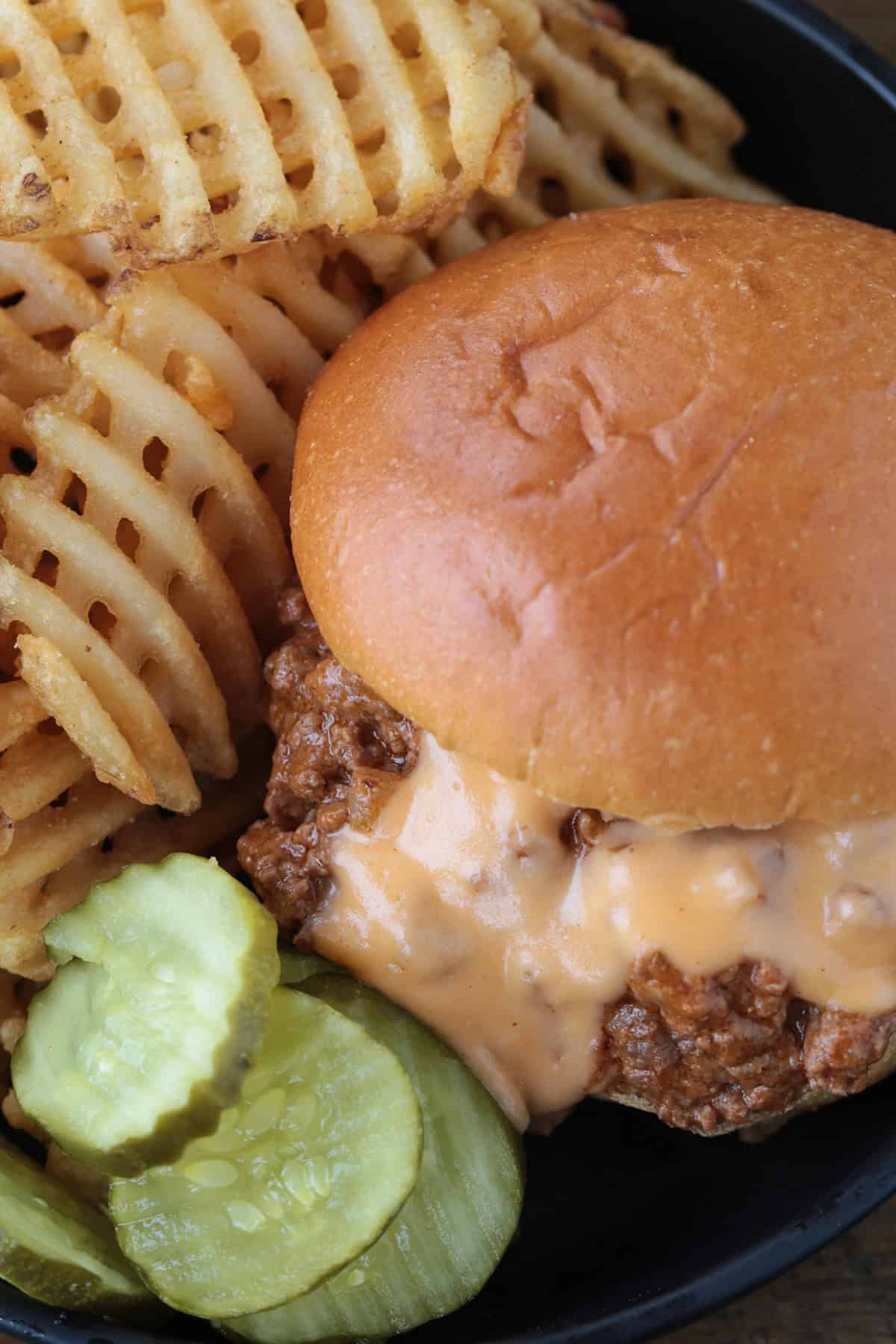 top view of a cheesy sloppy joe on a plate with fries and pickles
